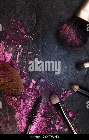 Make-up brushes with broken cosmetics, shot from the top on a dark background forming a frame with a place for text, a beauty design template for a ma Stock Photo