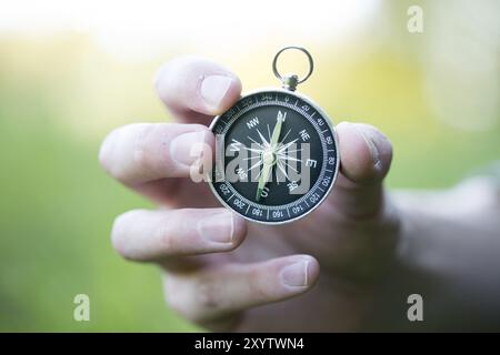 Young man on an adventure is holding a compass in his hand for finding is route Stock Photo