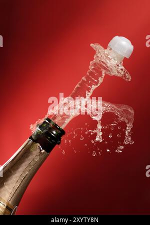 Cork flying out of a bottle of champagne. Isolated conceptual image on red background Stock Photo