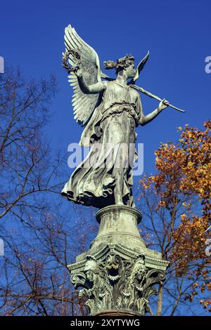 Statue of an angel on a column in bright sunshine in autumn with clear blue skies Stock Photo