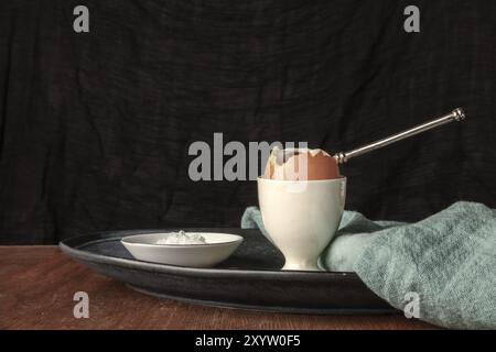 A soft-boiled egg with salt, a side view photo on a dark background with a place for text Stock Photo