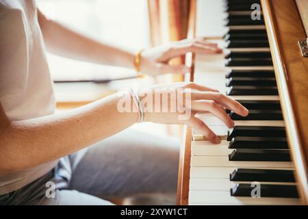 Young girl is practicing piano at home. Clipping of piano and hands Stock Photo