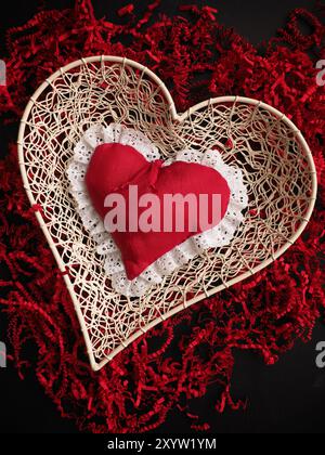 Red fabric heart shape on red shredded paper, love concepts Valentines Day or Mothers Day background Stock Photo