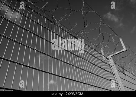 Barbed wire on a high fence Stock Photo