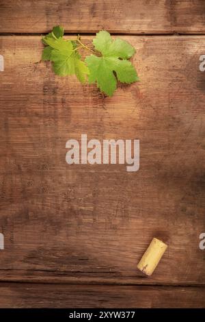 A design template for a wine menu or tasting invitation. A vine leaf and a wine cork, shot from the top on a dark rustic wooden background with a plac Stock Photo