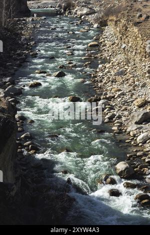 The stormy stream of a mountain river with splashes goes around the ...