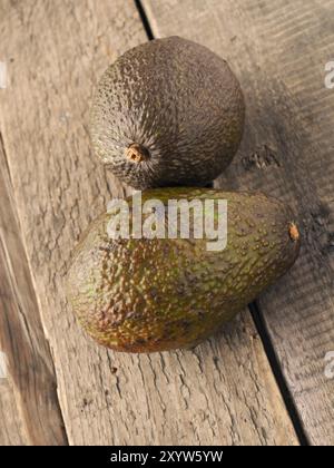 Two avocados on a rustic wooden kitchen table Stock Photo