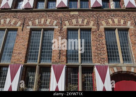 Detailed view of a brick building with large windows and red and white shutters under a blue sky, Xanten, Lower Rhine, North Rhine-Westphalia, Germany Stock Photo