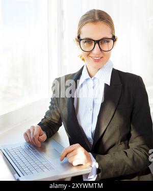Young pretty business woman wearing eyeglasses with notebook in the office Stock Photo