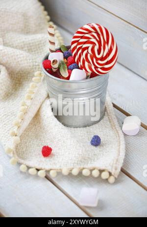 Colorful candies in a small bucket on light wooden background Stock Photo