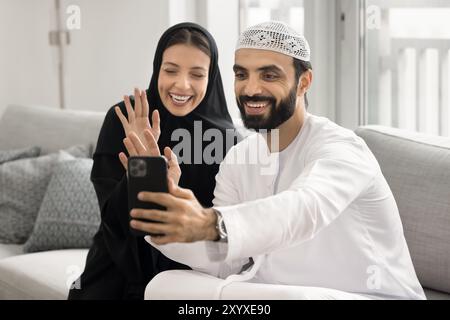 Cheerful Arabic husband and wife talking on video call Stock Photo