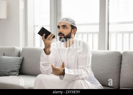 Serious bearded Muslim man talking on audio call Stock Photo