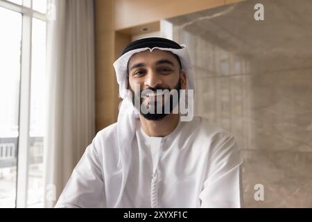 Cheerful handsome Arab businessman in keffiyeh looking at camera Stock Photo