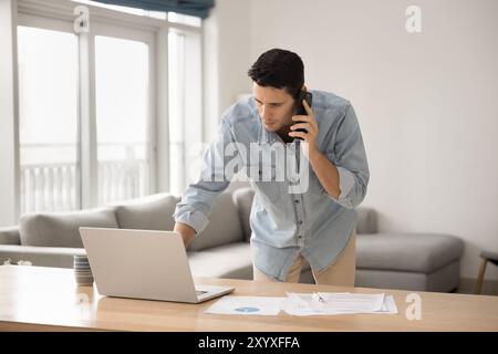 Serious busy Latin freelancer man talking on mobile phone Stock Photo