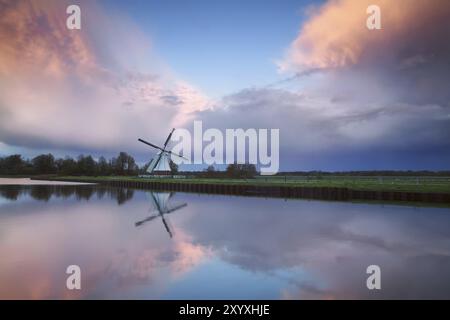 Beautiful sunset over Dutch windmill by river, Netherlands Stock Photo