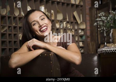 Young woman sits in an armchair on a background of vintage interior Stock Photo