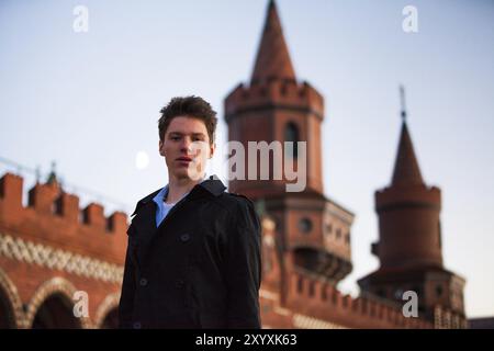 Male youth in front of the Oberbaum Bridge in Berlin Stock Photo