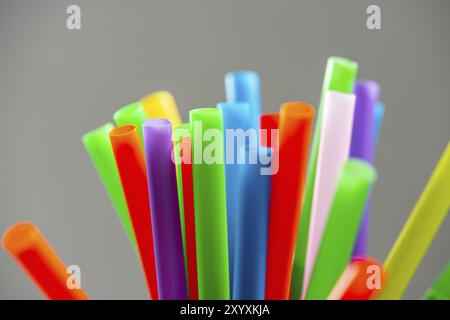 Multi colored plastic straws in a jar in front of a grey background Stock Photo