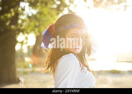 Happy slim tan woman in jeans dancing on the beach in sunset Stock Photo