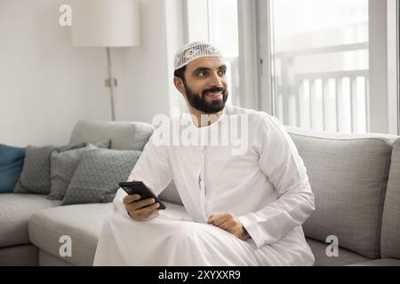 Positive handsome Middle Eastern man holding mobile phone Stock Photo