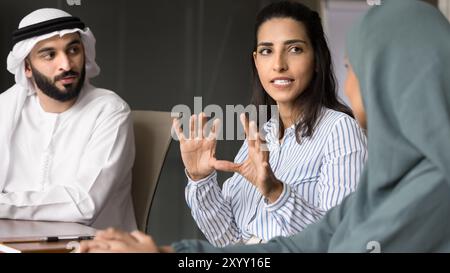 Inspired motivated Hispanic business woman talking to Arabian colleagues Stock Photo