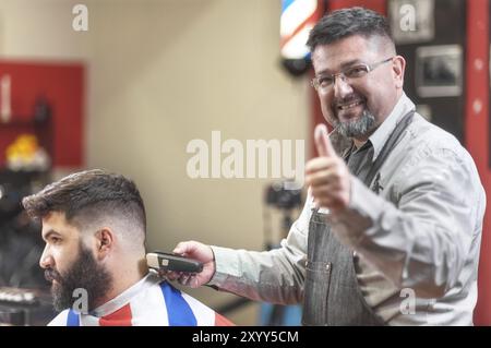 Portrait of a barber working while showing thumb up. Positive approval sign Stock Photo