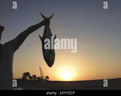 Young man with big Queen fish that was catched by him on a ocean Stock Photo