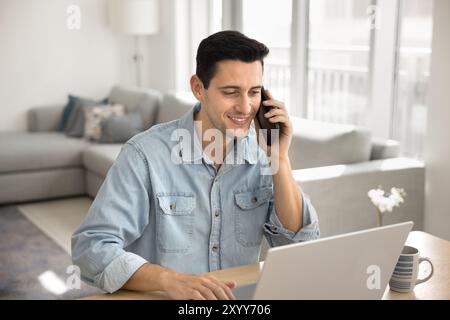 Positive young Hispanic freelance manager man talking on cellphone Stock Photo