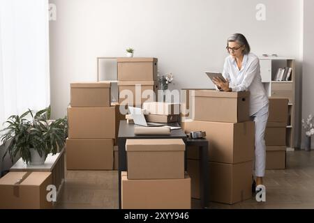 Woman using tablet engaged in managing orders and inventory workflow Stock Photo