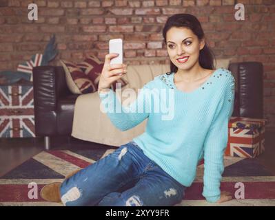 Young beautiful woman sitting with smart phone. Toned picture Stock Photo
