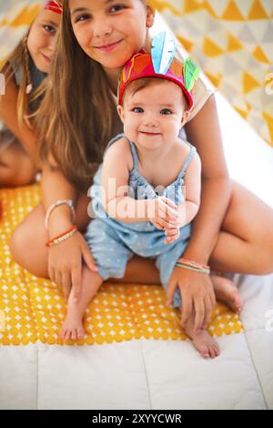 Three cute girl playing indians together indoors Stock Photo