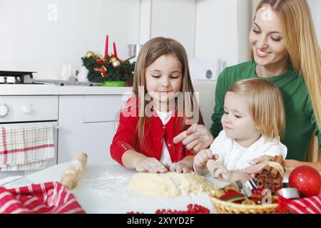 Two adorable girls with her mother baking Christmas cookies in the kitchen Stock Photo
