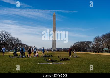 Washington, DC, USA -- February 3, 2020. A photo of a group of cyclists standing on the National Mall; their bicycles lie in the grass with the Washin Stock Photo