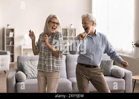 Happy retired couple dancing in cozy living room Stock Photo
