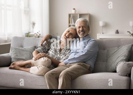Cheerful mature relaxed spouses posing for camera seated on couch Stock Photo