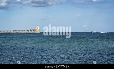 Blyth Lighthouse, the pier and a wind turbine on the North Sea Coast, seen on South Beach in Blyth, England, UK Stock Photo