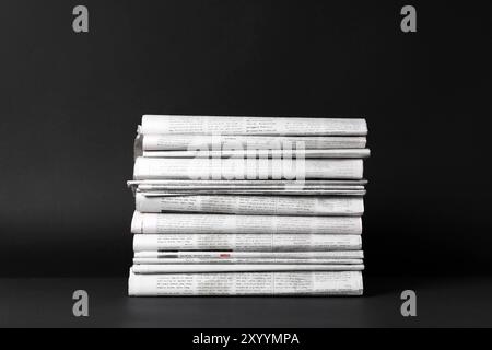 Stack of newspapers in different languages on black background Stock Photo