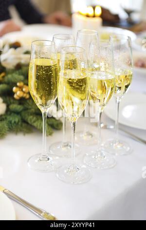 Champagne into a glasses standing on the Christmas table. Close up Stock Photo