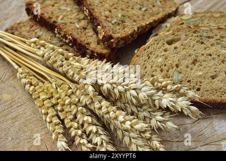 Top view of sliced wholegrain bread on a wooden table. Different types of bread and ears of grain Stock Photo