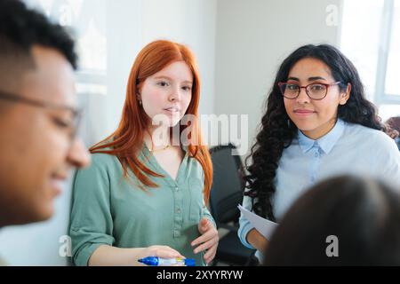 Contemporary co-working space with young professionals or students collaborating on projects, demonstrating teamwork. Stock Photo