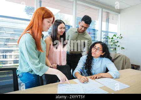 Young professionals or students collaborating in a bright co-working space, focused on teamwork and creative development Stock Photo