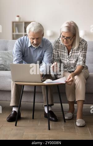 Serious older spouses pay household bills using laptop Stock Photo