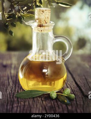 Olive oil and olive branch on the wooden table over nature background Stock Photo