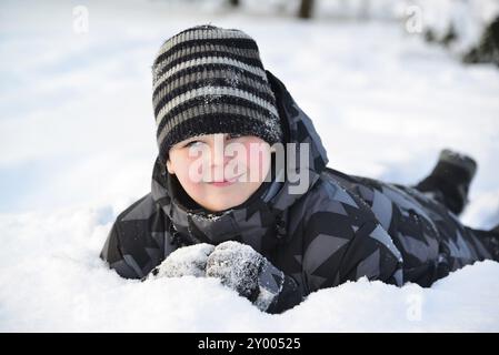 Teen boy lies in the snow in the winter forest Stock Photo