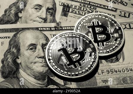 Two Bitcoins on hundred dollars bills. Closeup, macro shot Stock Photo