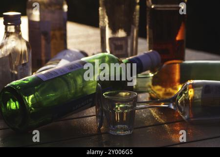 Bottles, alcohol, glass, backlight, silhouette, alcohol problem, various bottles standing and lying on a table and glowing in the light of the sun Stock Photo