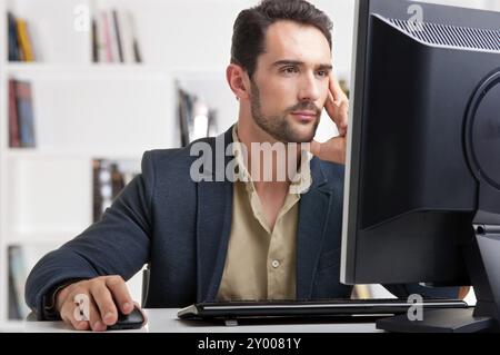 Man looking at a computer screen, thinking about the job at hand Stock Photo