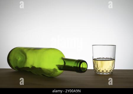 Green wine bottle and a glass of white wine on a wooden table Stock Photo