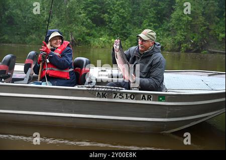 Alaska's great angling opportunities include 5 species of salmon. Guide Dan Suprak nets a big silver salmon for his client. Stock Photo