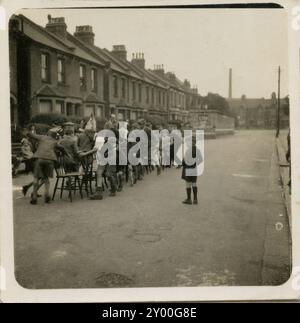 1950s, historical photo, children at a having fun playing a game at a street party outside, England, UK. The tradition of a party in a street for the local children and reisdents dates back to the 'Peace Teas', held after the first World War in 1919 when the Treaty of Versalilles was signed and 19th July was declared 'Peace Day'. Since then street parties have been held in Britain on all major national days of celebration; in 1945 on VE Day & VJ day, the Festival of Britain in 1951 and the Queen's Coronation in 1953  and other special occasions, such as the 1977 Queen's Silver Jubilee. Stock Photo